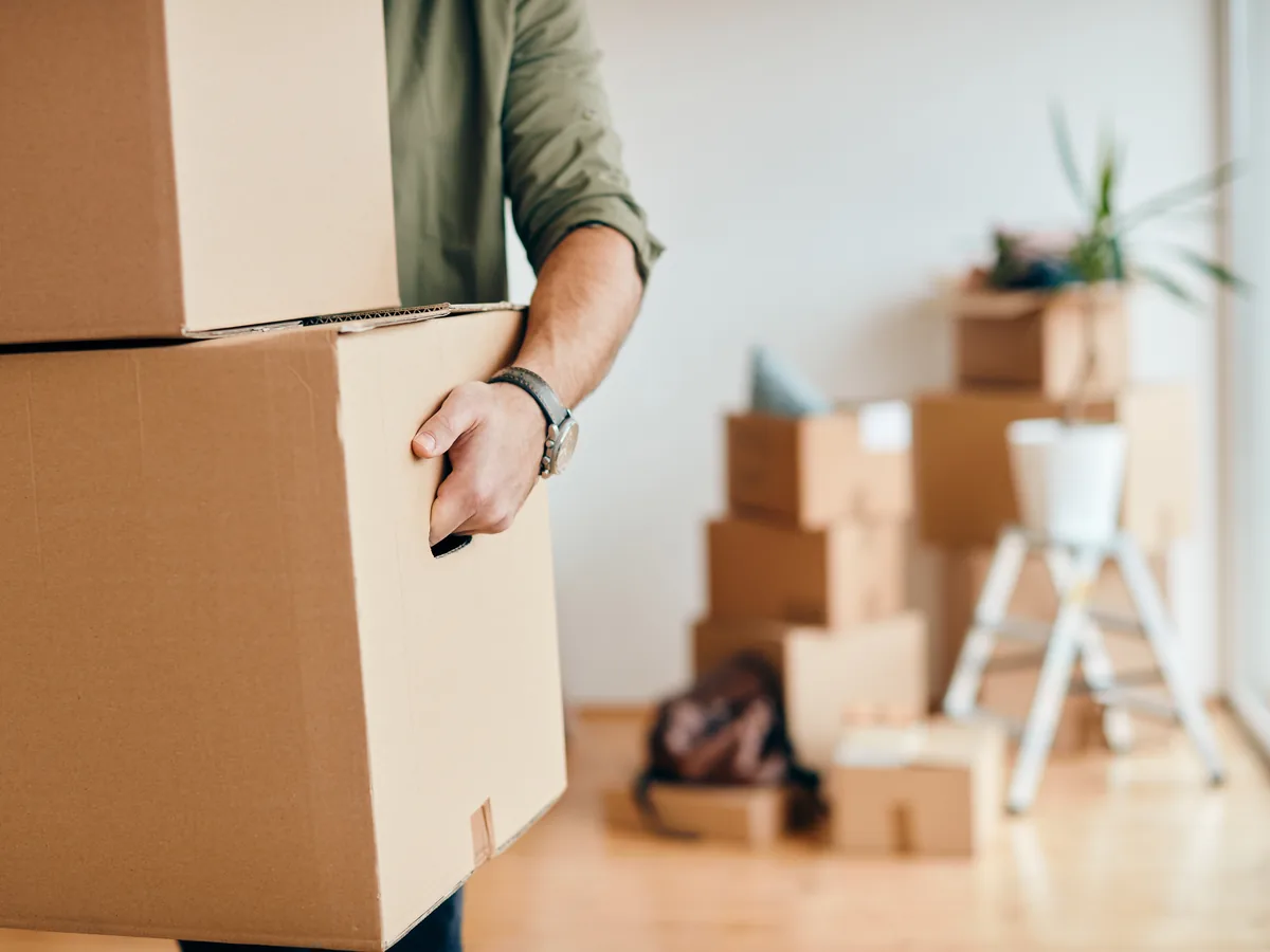 Intervenant portant des cartons lors du vidage d'un logement, autres cartons empilés à l'arrière-plan