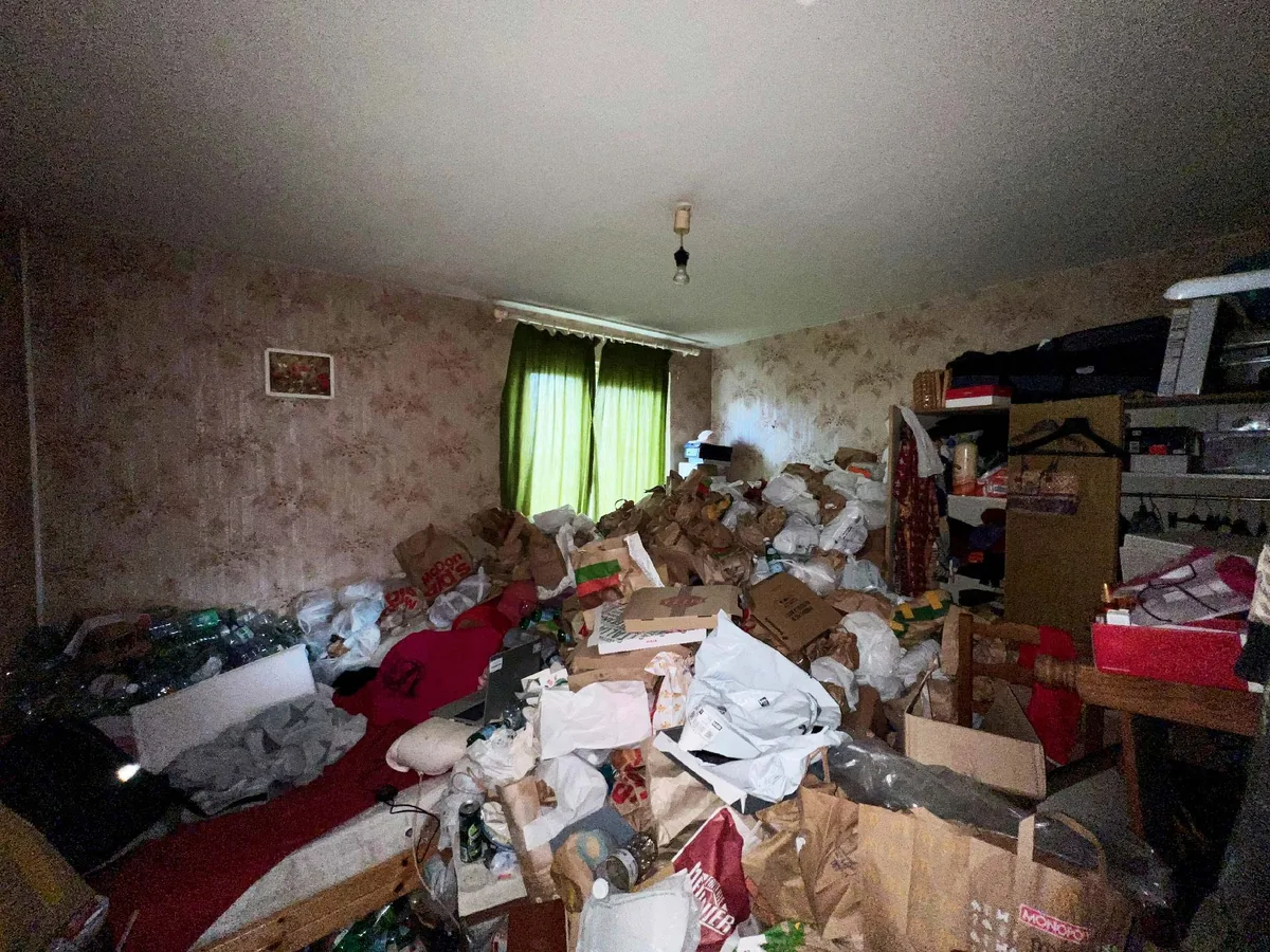 Pièce d'habitation en accumulation sévère, sacs et objets entassés sur toute la surface au sol